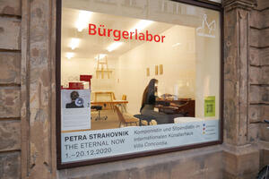 Bild vergrößern: Bild: Petra Strahovnik sitzt an einem Klavier hinter dem Fenster im Bürgerlabor.
