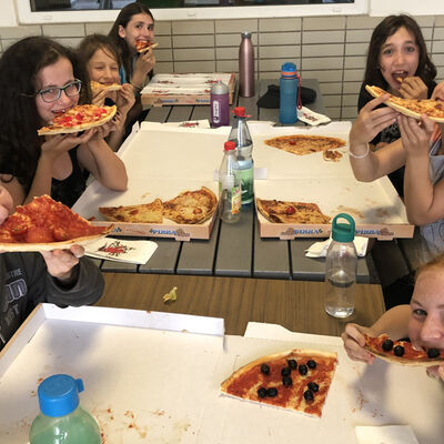 Bild vergrößern: Auf dem Bild sind die Mädchen beim Pizzaessen zu sehen.