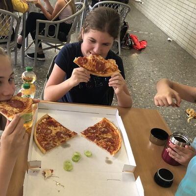 Bild vergrößern: Auf dem Bild sind die Mädchen beim Pizzaessen zu sehen.