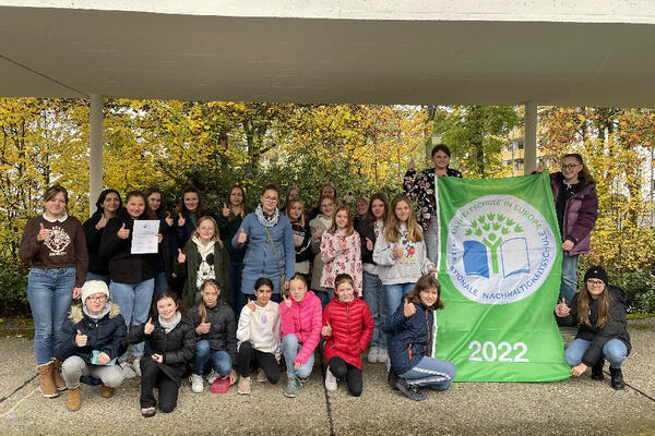 Bild vergrößern: Auf dem Gruppenfoto sind die Wahlfachteilnehmerinnen der Umweltgruppe sowie die FÖSJ-Mädchen und ein Teil unserer Umweltsprecherinnen am Eichendorff-Gymnasium zu sehen. Sie halten gemeinsam die Flagge mit der Auszeichnung »Umweltschule in Europa/ Internationale Nachhaltigkeitsschule« für das Jahr 2022.