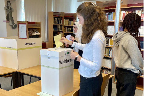 Bild vergrößern: Eine Schülerin beim Einwurf ihres Stimmzettels in die versiegelte Wahlurne.